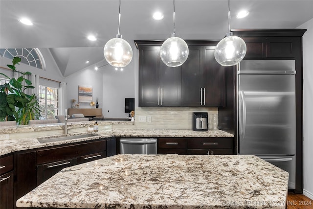 kitchen with appliances with stainless steel finishes, hanging light fixtures, vaulted ceiling, and sink