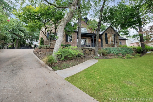 tudor-style house featuring a front yard and covered porch