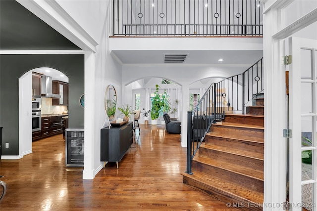 foyer featuring wood-type flooring, a high ceiling, and ornamental molding