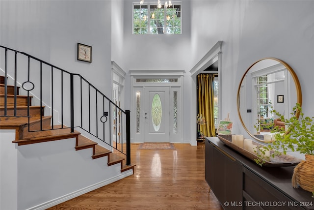 foyer with a notable chandelier, light hardwood / wood-style floors, and a high ceiling