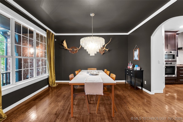 dining room featuring crown molding, dark hardwood / wood-style flooring, and a chandelier