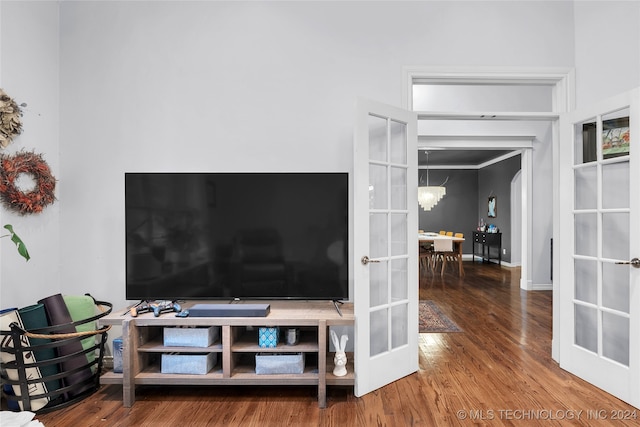 unfurnished living room featuring a notable chandelier, hardwood / wood-style flooring, and french doors