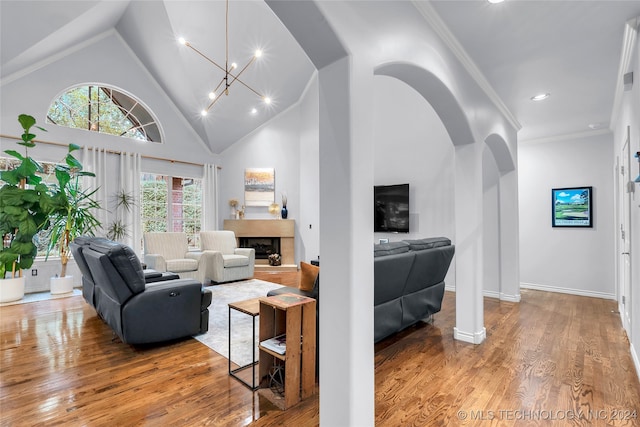 living room featuring ornamental molding, an inviting chandelier, high vaulted ceiling, and hardwood / wood-style flooring