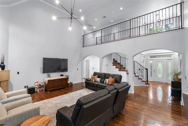 living room featuring hardwood / wood-style flooring, a towering ceiling, and ornamental molding