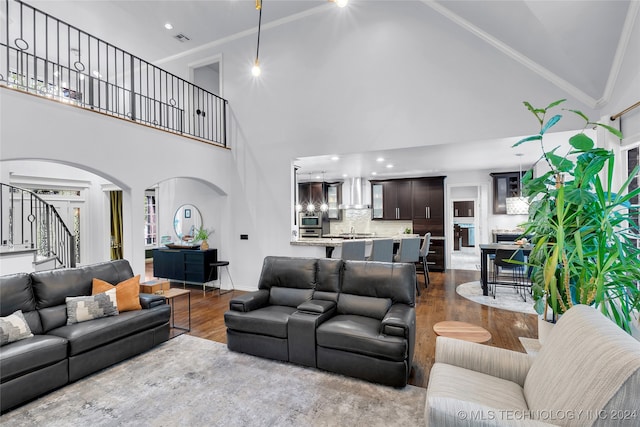 living room featuring hardwood / wood-style flooring, crown molding, and high vaulted ceiling