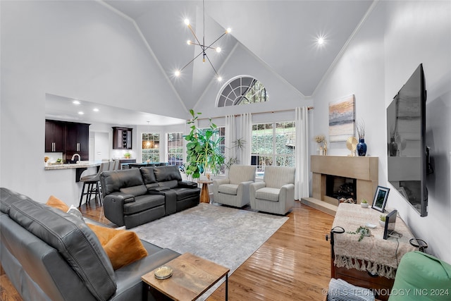 living room featuring high vaulted ceiling, light wood-type flooring, a chandelier, and a premium fireplace