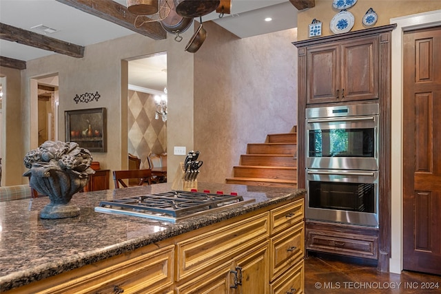 kitchen featuring dark stone countertops, dark tile patterned floors, beamed ceiling, stainless steel appliances, and a chandelier