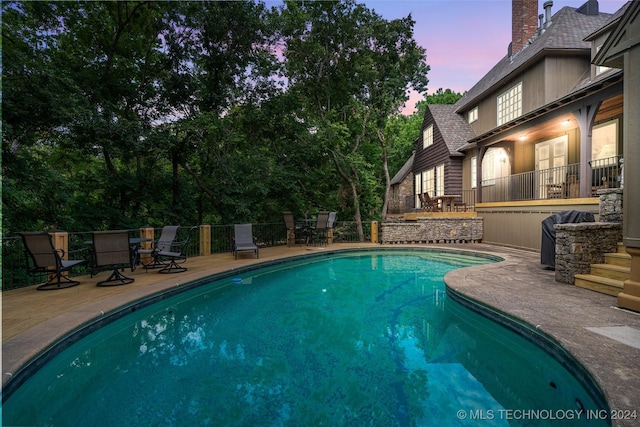 pool at dusk featuring a patio area