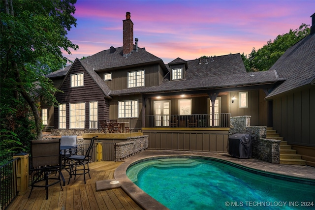 pool at dusk with area for grilling and a patio area