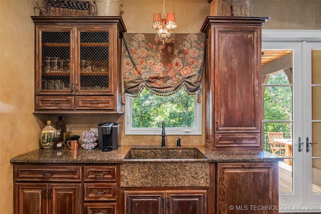 bar featuring dark brown cabinets, sink, french doors, and an inviting chandelier