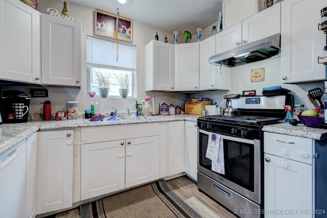 kitchen with light stone countertops, white cabinetry, and gas range