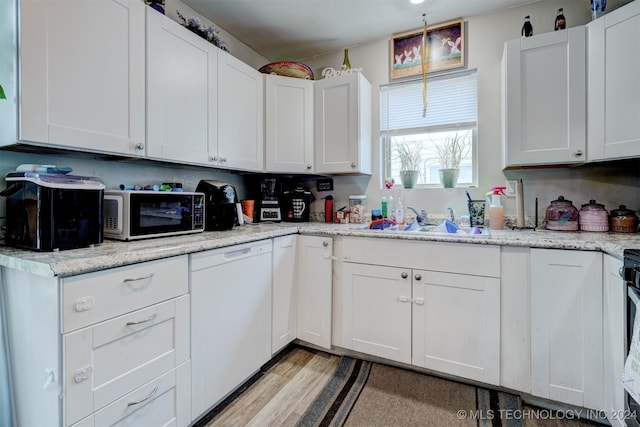 kitchen with white cabinets, light wood-type flooring, sink, white appliances, and light stone countertops