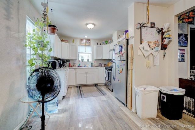 kitchen featuring white cabinets, appliances with stainless steel finishes, light hardwood / wood-style flooring, and a healthy amount of sunlight