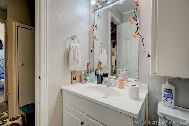 bathroom with ornamental molding, vanity, and toilet