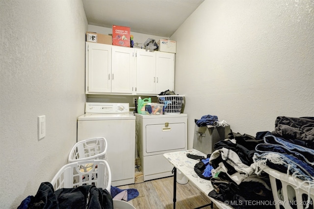 clothes washing area with washer and clothes dryer, light hardwood / wood-style flooring, and cabinets