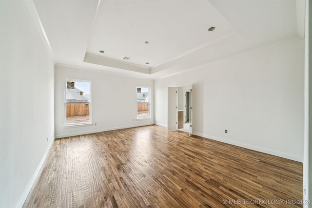 unfurnished living room featuring a raised ceiling, ornamental molding, and wood-type flooring