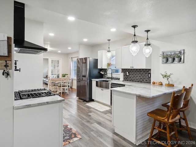 kitchen with stainless steel appliances, range hood, kitchen peninsula, and white cabinets