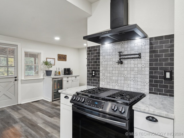 kitchen with range hood, light stone counters, white cabinets, stainless steel range with gas cooktop, and beverage cooler