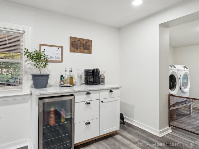 bar featuring white cabinetry, beverage cooler, dark hardwood / wood-style flooring, washing machine and dryer, and light stone countertops