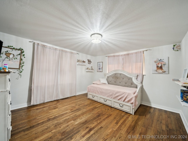 bedroom featuring a textured ceiling and dark hardwood / wood-style flooring