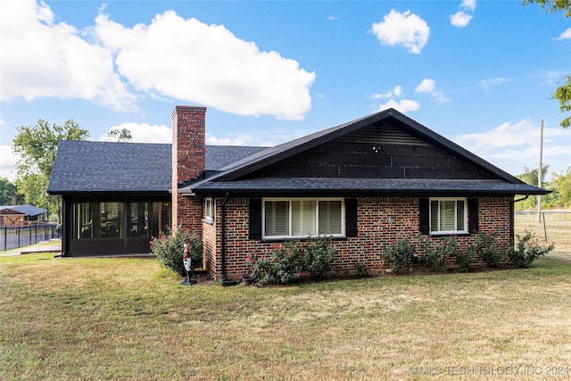 rear view of property with a lawn and a sunroom