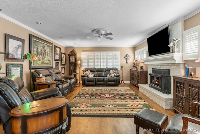 living room featuring light hardwood / wood-style floors, a fireplace, ornamental molding, and ceiling fan