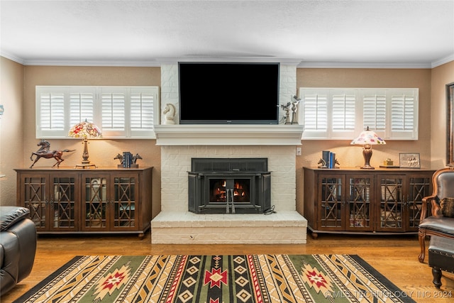 living room featuring a brick fireplace, crown molding, and wood-type flooring