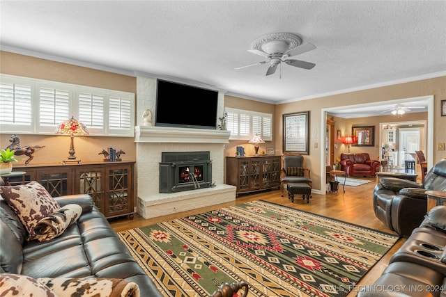 living room featuring ceiling fan, ornamental molding, a fireplace, and hardwood / wood-style floors