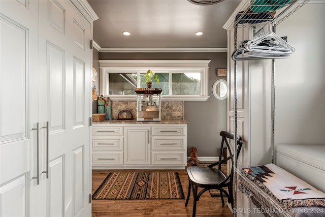 interior space with light stone countertops, crown molding, dark hardwood / wood-style flooring, and white cabinets