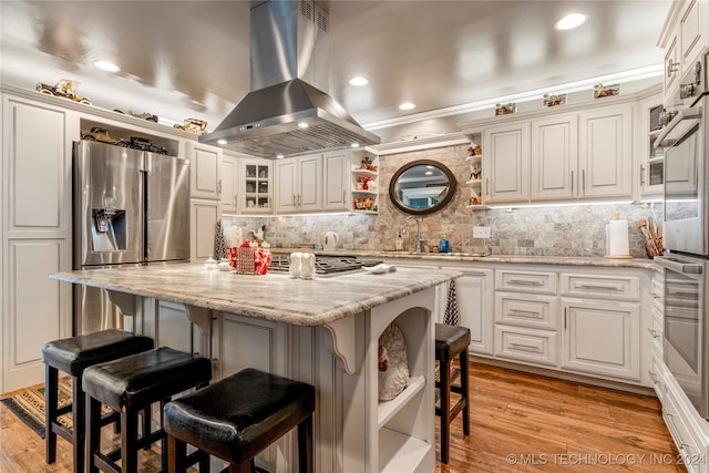 kitchen with light wood-type flooring, island range hood, a kitchen island, and a breakfast bar