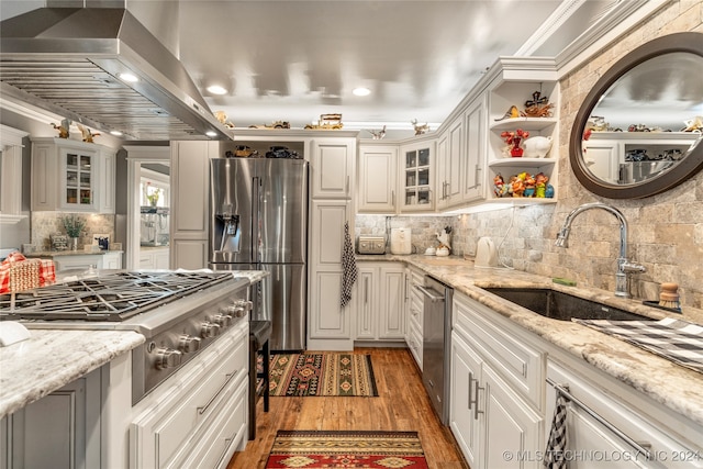 kitchen featuring light stone countertops, appliances with stainless steel finishes, wall chimney exhaust hood, and sink