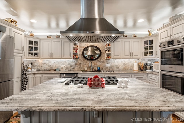 kitchen with a kitchen breakfast bar, island range hood, stainless steel appliances, and a spacious island