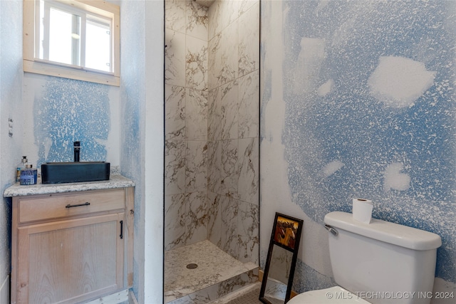 bathroom featuring toilet, vanity, and tiled shower