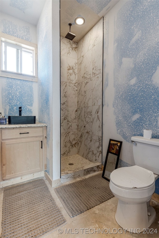 bathroom with a textured ceiling, tile patterned floors, tiled shower, vanity, and toilet