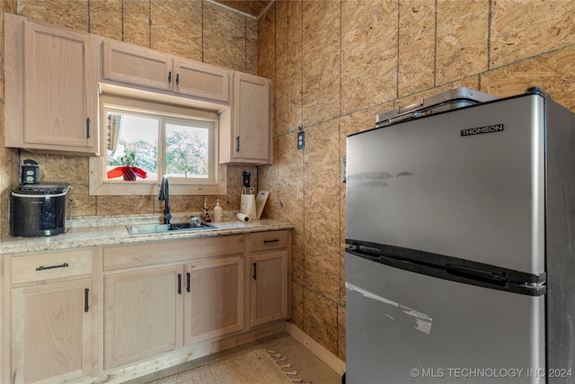 kitchen featuring light brown cabinetry, sink, and stainless steel fridge