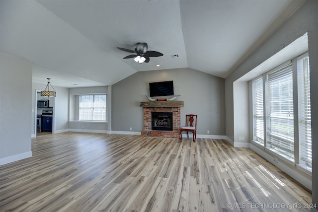 unfurnished living room with light wood-type flooring, a fireplace, lofted ceiling, and ceiling fan