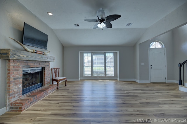 unfurnished living room featuring light hardwood / wood-style flooring, lofted ceiling, ceiling fan, and a fireplace