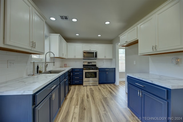 kitchen featuring blue cabinets, white cabinets, sink, stainless steel appliances, and light wood-type flooring