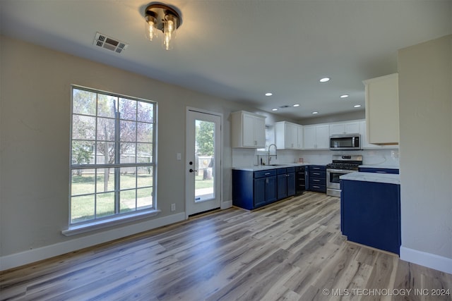 kitchen featuring a wealth of natural light, stainless steel appliances, light hardwood / wood-style floors, and white cabinetry