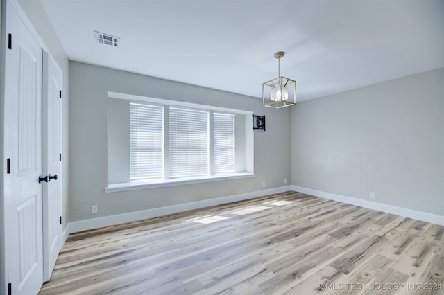 spare room with a notable chandelier and light hardwood / wood-style floors