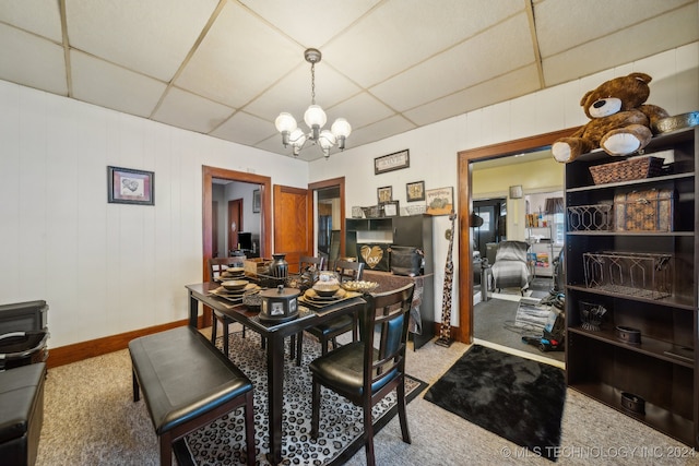 carpeted dining room with a paneled ceiling and a notable chandelier