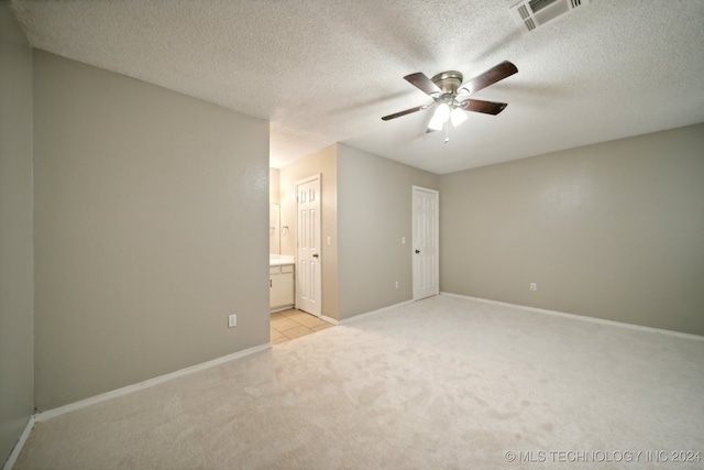 interior space with a textured ceiling, ceiling fan, and light colored carpet