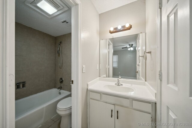 full bathroom with vanity, a textured ceiling, tiled shower / bath combo, ceiling fan, and toilet