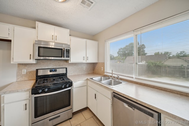 kitchen featuring white cabinets, light tile patterned floors, sink, backsplash, and appliances with stainless steel finishes