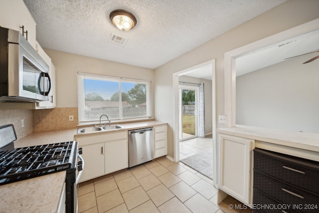 kitchen with stainless steel appliances, white cabinetry, a textured ceiling, and light tile patterned flooring