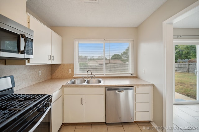 kitchen featuring white cabinets, light tile patterned flooring, sink, stainless steel appliances, and decorative backsplash