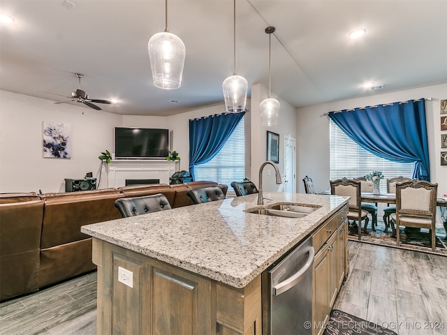 kitchen featuring ceiling fan, hanging light fixtures, a kitchen island with sink, dishwasher, and light hardwood / wood-style floors