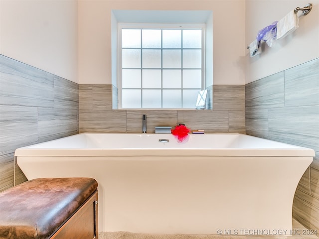 bathroom with tile walls, a bathing tub, and plenty of natural light