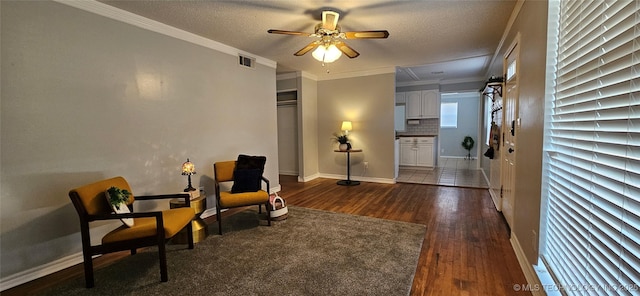 sitting room featuring ceiling fan, dark hardwood / wood-style floors, ornamental molding, and a textured ceiling