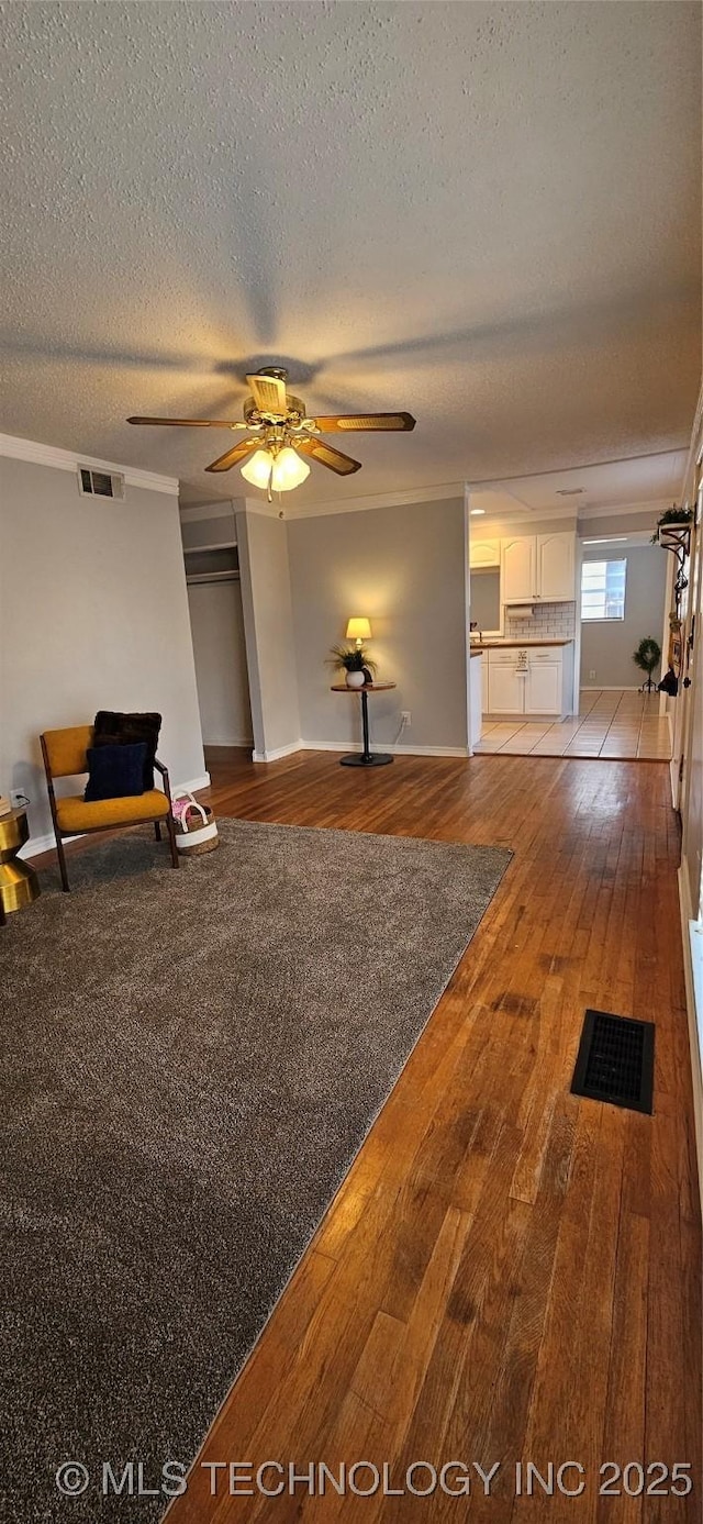 unfurnished living room with a textured ceiling, ceiling fan, and light hardwood / wood-style flooring